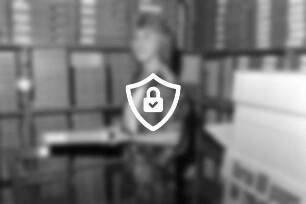 Mitarbeiterin [Name maskiert] vom Kreisarchiv steht vor Regalen mit Archivschachteln und hält eine davon in [Name maskiert]