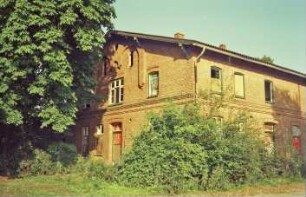 Am Markt (10): traufständiges Backsteingebäude mit umlaufendem Gesims: Straßenfront, Teilansicht mit Eingangstür: Giebelseite mit Seitentür