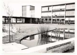 Grünflächen am Max-Planck-Gymnasium, Düsseldorf: Schulgebäude mit Garten, Plattenweg, Wasserbecken, Sitzmauer