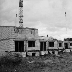 Stadtteil Gartenholz: Reiheneigenheime in Bau: Rohbau: Arbeiter mit Schaufeln, auf Stockwerk: Stapel mit Mauersteinen: Baukran: im Vordergrund großer Findling