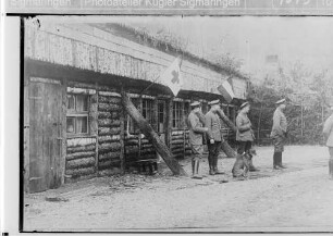 Offiziere vor einer Rot-Kreuz-Unterkunft in Blockbauweise