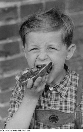 Porträt eines kleinen Jungen beim Essen eines Brots