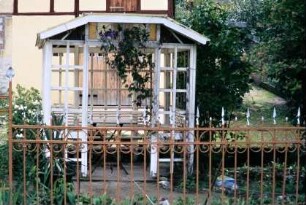 offene Gartenlaube und schmiedeeiserner Zaun