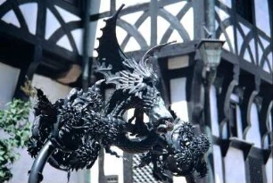 Brunnendetail: kunstschmmiedeeiserne Plastik über dem Brunnen