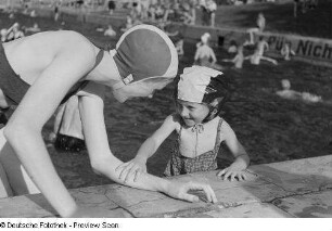 Portrait Renate Rössings in Badebekleidung mit einem kleinen Mädchen spielend im Freibad