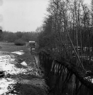 Ehlersberg: Alster: rechts Sträucher und Bäume: links Wiesen: hinten links alte Alsterschleuse und Brücke mit Geländer: im Hintergrund Wald: Winter
