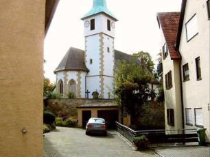 Ansicht von Nordosten mit Kirche (im Kern Gotisch-spätere Überarbeitung) über Kirchhofmauer (Wehrgang abgetragen) in erhöhter Lage am (ehemaligen) Ortsrand