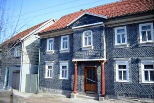 verschiefertes Haus mit auf Säulen stehendem Zwerchhaus
