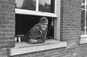Zweiter Weltkrieg. Niederlande unter deutscher Besatzung. Porträt eines Wehrmachtsangehörigen, aus einem Fenster schauend (wohl bei Den Haag)