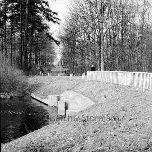 Alster: Wulksfelder Weg: Wulksfelder Schleuse: Schleusenbrücke mit Geländer: hinten Mitte Person auf Brücke: vorn rechts Uferböschung: hinten Bäume: im Hintergrund Mitte Gebäude