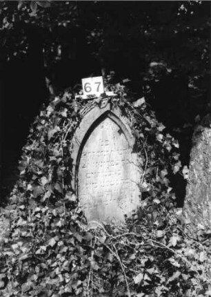 Grabstein 67 (Index: 100084979) Maße HxBxT: 120x50x20 cm Beschreibung: Stele, Spitzbogenabschluß, Schriftfelder eingetieft: Grabstein 67