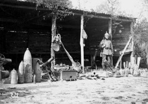 Erster Weltkrieg : Deutscher Soldat vor Schuppen mit unterschiedlichen Munitionshülsen