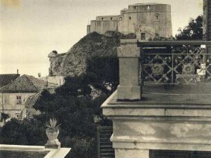 Blick von einer Terrasse zu einer Burg. Felsvorsprung links mit Tusche als Schafskopf gestaltet
