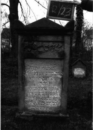 Grabstein 51 (Index: 99804801) Material: Sandstein Zustand: verwittert Beschreibung: Stele, Giebel mit Eckakroteren, eingetieftes Schriftfeld rechteckig Symbolik: Eichblätter mit Eichel: Grabstein 2/23