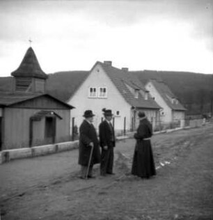 Bebra. Ortsteilansicht. Ordenspriester im Gespräch mit zwei Senioren vor einer Kapelle