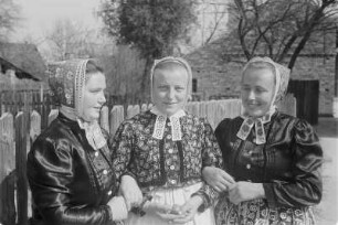 Mädchen in Schleifer Tracht aus Rohne auf der Singebank in Rohne. : Holcy w Slepjanskej drasće z Rowneho na spěwarskej ławcy w Rownom.