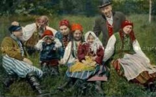 Männer, Frauen und Kinder in russisch-polnischer Volkstracht auf der Wiese sitzend (zweisprachig)