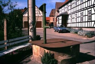 Straße mit anliegenden Fachwerkhäusern, Wasserpumpe