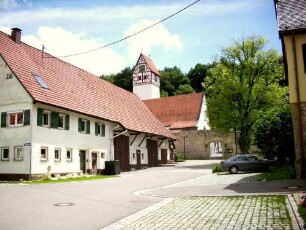 Ansicht von Norden mit Kirche in Kirchhof über Kirchhofmauer in Lage zu ebener Erde am Ortsrand mit ansteigendem Berghang gegen Süden
