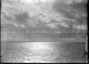 Mitternachtssonne hinter dunklen Wolken, Spiegelung im ruhigen Meer, Nordlandreise, Norwegen