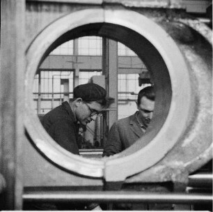 Rostock. VEB Dieselmotorenwerk Rostock. Blick durch eine Lagerbuchse auf zwei Arbeiter