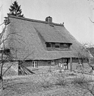 Haus mit Reetdach: ehemalige Voßsche Räucherkate: davor Garten: rechts und links Bäume