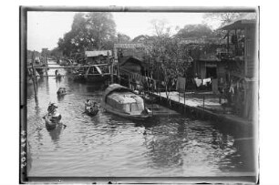 Leben am Fluss : Phetchaburi. Blick auf den von Häusern gesäumten Fluss mit Booten, 1909/1910