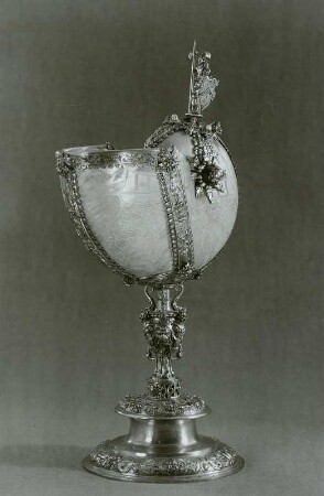 Nautiluspokal auf vasenförmigem Schaft mit 3 Bügeln und bärtigen Männerköpfen, als Bekrönung: geharnischter Ritter in Tracht des 17. Jh. mit Schild und Hellebarde