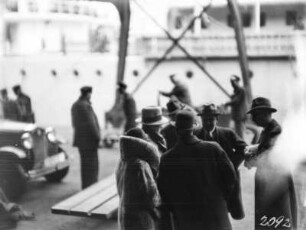 Löschen der Ladung in Hamburg : Im Hintergrund das Löschen der Ladung nach der Ankunft der Schomburgk Expedition in Hamburg. Personengruppe im Vordergrund möglicherweise Teilnehmer der Expedition.