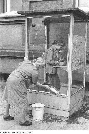 Jana Richter in einer Telefonzelle und alte Frau beim Saubermachen dieser Telefonzelle, aufgenommen in Gotha