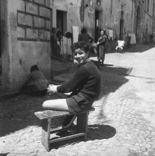 Nicastro, Junge auf einem Schemel sitzend in einer belebten Straße der Altstadt