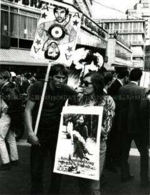 Mann und Frau auf einer Anti-Vietnamkriegs-Demonstration, der Mann trägt ein Plakat mit Rudi Dutschke