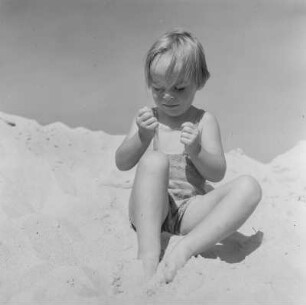 Ein Kind spielt mit Sand am Strand