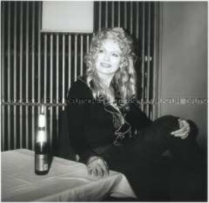 Frau mit Locken an einem Tisch sitzend (Altersgruppe 18-21)