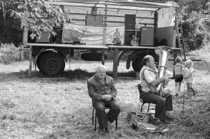 Volksfest : Colditz. Vier Personen im Grünen vor einem LKW-Anhänger, der zu einer Bühne umfunktioniert ist. Zwei Männer die auf Stühlen sitzen. Der eine lauscht dem anderen beim Tuba spielen zu. Hinter den Männern tanzen zwei kleine Kinder zur Musik der Tuba.