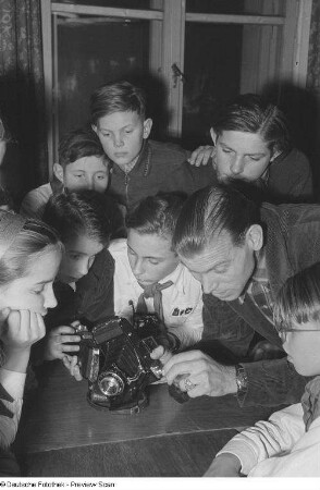 Pioniere während des Erklärens eines Fotoapparates zuhörend