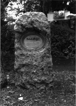 Grabstein 29 (Index: 100101434) Material: Kalkstein, weiße Marmorplatte Zustand: gut Maße HxBxT: 135x57x28 cm Beschreibung: grob stelenhaft behauener Stein, ovale Schriftplatte: Grabstein 29