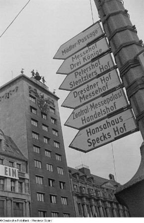 Hinweisschilder zu den Messehäusern an einem Lichtmast vor dem Kroch-Hochhaus