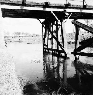 Trave: Holzbrücke in baufälligem Zustand: hinten Wiesen und Bäume