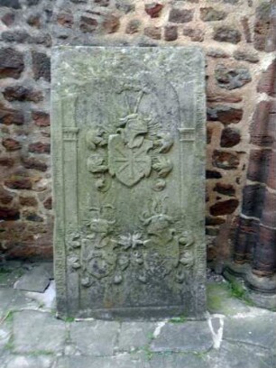Totenkirche (Romanische Gründung)-Seitenschiff Nord Innen - Nordwand - Exemplarischer Grabstein mit Textkartusche sowie Wappe in Hochrelief (teils stark verwittert - aus ehemaligem Kirchhof)