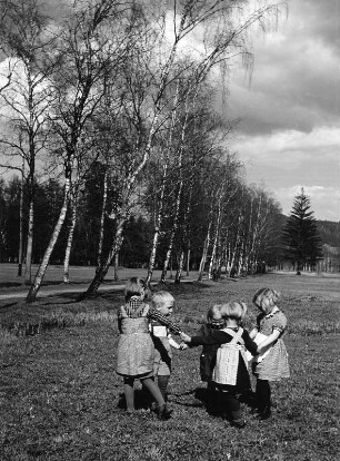 Kinderbilder. Kinder beim Ringelreihen auf einer Wiese
