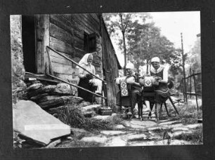 Klöpplerinnen beim Hacher-Sachs-Haus : Steinbach. Klöppelnde Frauen vor einem Blockhaus (Hacher-Sachs-Haus)