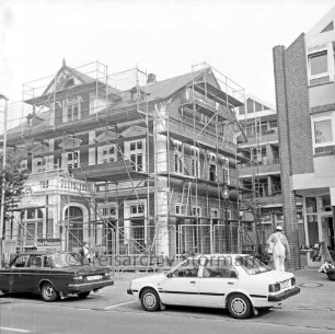 Rathausstraße: Renovierung eines Wohn- und Geschäftshauses aus der Zeit um 1900: Gerüst, Bauzaun, Handwerker: umgeben von Neubauten: davor parkende Autos