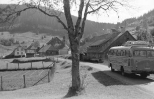 Äule: Postbus mit Ort auf Straße und Berge