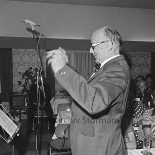 Männergesangverein "Liedertafel Siek von 1886" e.V.: 90-jähriges Jubiläum: Konzert im Gasthof "Zur Traube": Chorleiter Gerhard Konert: rechts dahinter Tische mit Zuhörern