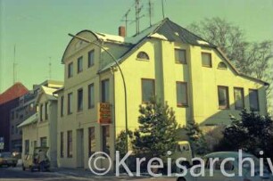 Königstraße 21: Alte Mädchenschule [ehemalige Winter'sche höhere Töchterschule]: traufständige Straßenfront, Mittelrisalit mit Bogendach, Eingangstür, Firmenschild Taxiunternehmen: Giebelseite mit Lisenen