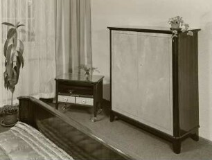 Kleiner Wäscheschrank (Herrenschrank) und Servierschränkchen : Herbstmesse der Möbelindustrie der DDR, 1956. Schlafzimmermöbel. Kleiner Wäscheschrank (Herrenschrank) und Servierschränkchen (1956; Entwicklungsstelle Zeulenroda) in Ausstellungskoje