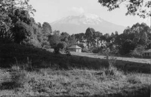 Berggipfel : Blick durch ein Dorf auf den Gipfel des Kibo (5895m) - der höchsten Erhebung des Kilimandscharo-Massives sowie des afrikanischen Kontinentes