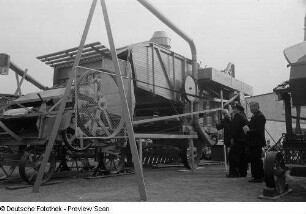 Besucher der Technischen Messe 1953 auf dem Freigelände Maschinen betrachtend