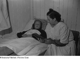 Krankenschwester liest einem kranken Mädchen aus einem Buch vor
